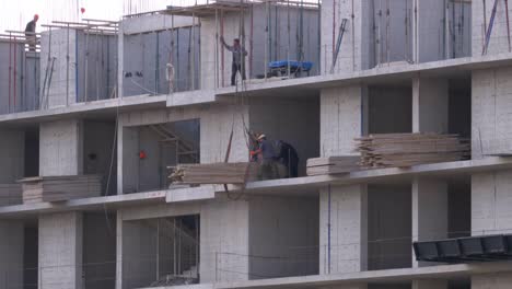 Trabajadores-en-una-obra-de-construcción.-Una-grúa-en-un-sitio-de-construcción-levanta-una-carga