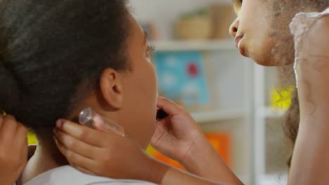 Hija-usando-lápiz-labial-en-la-cara-de-mamá