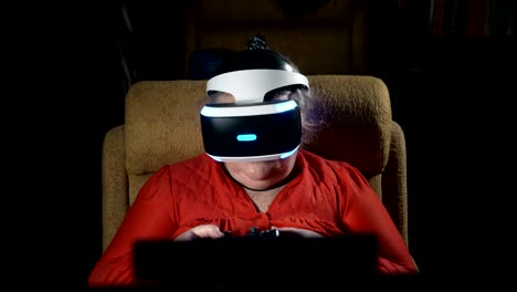 Elderly-woman-in-front-of-TV-screen-uses-VR-headset-and-wireless-gaming-controller