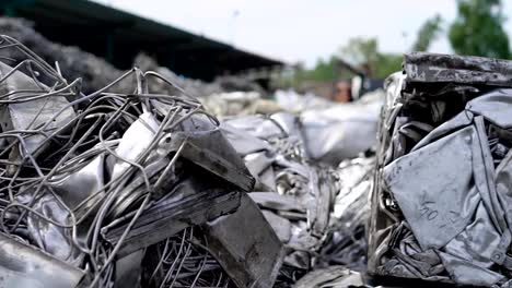 large-pressed-briquettes-with-metal-scrap-are-lying-on-a-junkyard-outdoor-in-cloudy-summer-day