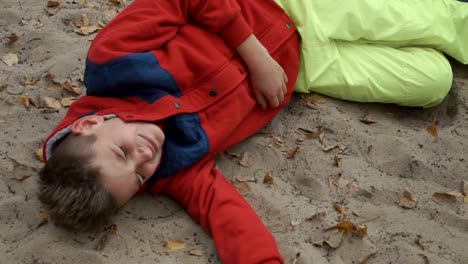 Little-crying-boy-lays-on-sand