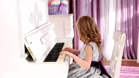 chica-rubia-juega-piano,-muchacha-en-un-vestido-con-un-cinturón-púrpura,-de-movimiento-lento.