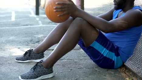 Sad-African-American-basketball-player-sitting-on-the-ground,-lack-of-motivation