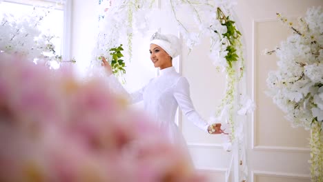 Hermosa-modelo-musulmana-en-blanco-boda-vestido-con-tocado-musulmán-posando-en-el-estudio