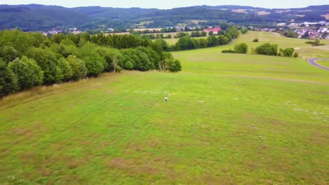 action-aerial-shot-a-boy-running-in-a-green-field-in-Europe