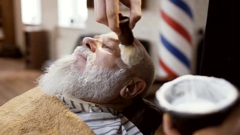 Barber-applies-shaving-cream-on-face-of-mature-man