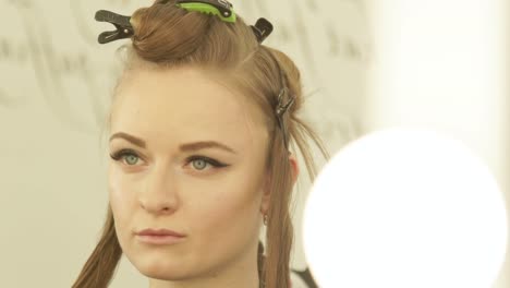 Portrait-young-woman-with-clamp-on-hair-during-haircutting-in-hairdressing-salon.-Female-hair-model-while-haircut-training-in-beauty-school