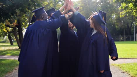 happy-students-in-mortar-boards-making-high-five