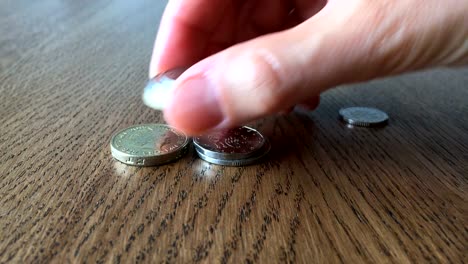 Concepto-de-crecimiento-del-dinero.-Mano-de-mujer-pone-monedas-en-la-mesa.-Close-Up