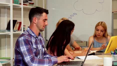 Handsome-male-student-showing-thumbs-up-while-using-laptop