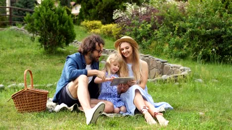 Family-using-digital-tablet-during-picnic-at-countryside