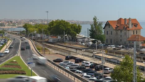 High-perspective-view-of-busy-traffic-near-Cascais,-Portugal-overlooking-the-Portuguese-Riviera.-Cascais-rail-station-is-visible-on-the-right