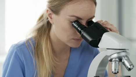 Mujer-bioquímico-con-microscopio-en-el-trabajo