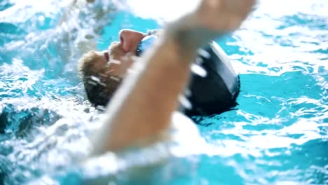 Disabled-man-swims-on-the-back-in-a-swimming-pool.-Close-up-shot.-Slow-motion