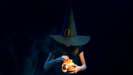 Girl-wearing-black-witch-hat-holding-jack-o'-lanterns