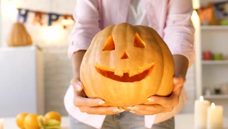 Female-hands-showing-funny-carved-pumpkin-into-camera,-handmade-work,-close-up