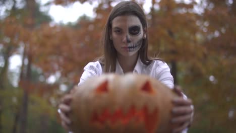 Víspera-de-Todos-los-Santos.-Mujer-con-un-maquillaje-de-Halloween-de-miedo-con-una-calabaza-en-las-manos