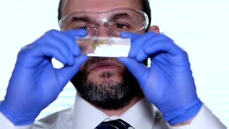 Biologist-examines-sample.-Science,-biology,-ecology.-Professional-scientist-wearing-protective-mask-working-with-herb-samples-in-his-laboratory.-Male-scientist-looking-at-plant-leaf-in-glass-slide.