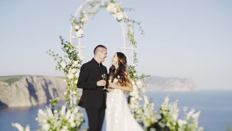 Married-couple-with-champagne-glass-in-decorated-arch