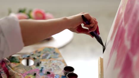 A-close-up-of-an-artist-painting-flowers-using-a-brush-and-a-palette.