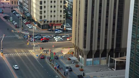 High-aerial-time-lapse-view-of-cars-on-a-traffic-light-and-crowds-of-people-crossing-a-street-in-the-city