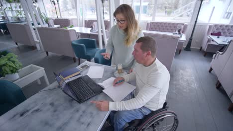 professional-training-of-invalid-senior-men-in-wheelchair-with-teacher-woman-using-laptop-computer-during-individual-teaching