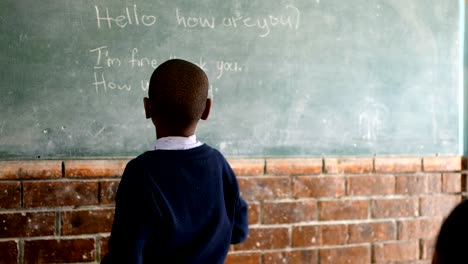 Schoolboy-writing-on-chalkboard-in-classroom-4k