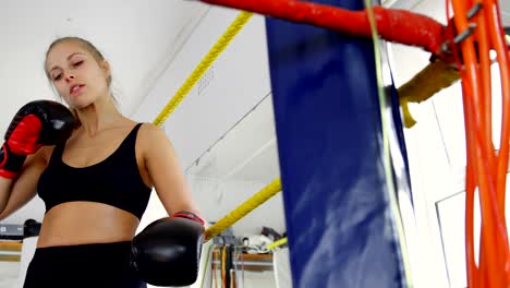 Female-boxer-relaxing-in-boxing-ring-4k