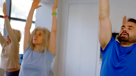 Trainer-assisting-senior-women-in-performing-yoga-4k