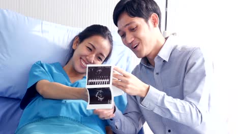 Pregnant-woman-and-husband-looking-to-x-ray-film-with-happy-emotion-together.-People-with-healthcare-and-medical-concept.