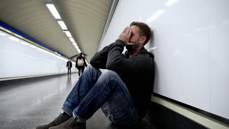 Trauriger-arbeitslose-junge-Mann-Weinen-leiden-Depression-betonen-sitzen-am-Boden-Straße-u-Bahn-Tunnel-suchen-verzweifelt-stützte-sich-auf-Wand-allein-in-emotionalen-Schmerz-Drogenmissbrauch-an-psychischen-Störungen-und-Alkoholismus.