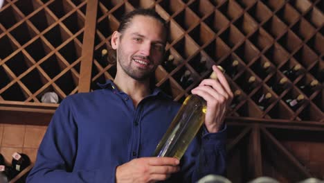 Smiling-Man-With-Bottle-Of-Wine-In-Cellar-At-Winery-Restaurant