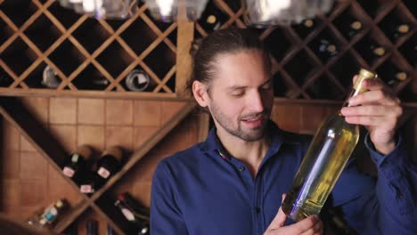 Smiling-Man-With-Bottle-Of-Wine-In-Cellar-At-Winery-Restaurant