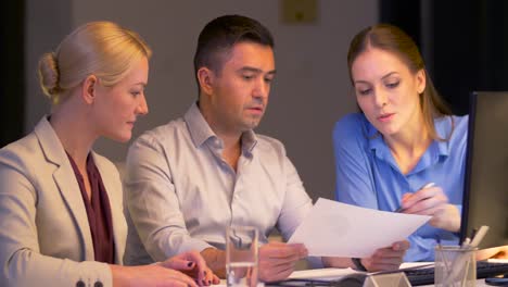 Business-Team-mit-Papieren-arbeiten-spät-im-Büro