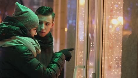 Pareja-mirando-el-escaparate-en-la-calle-en-la-noche