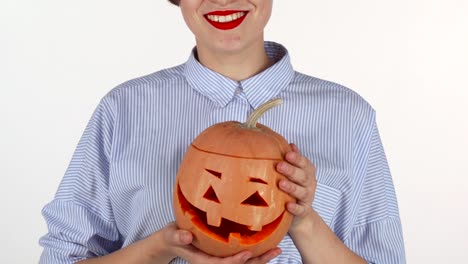 Woman-wearing-red-lipstick-holding-up-carved-halloween-pumpkin