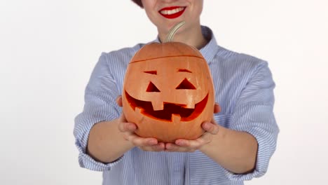 Red-lipped-woman-holding-out-carved-Halloween-pumpkin-to-the-camera