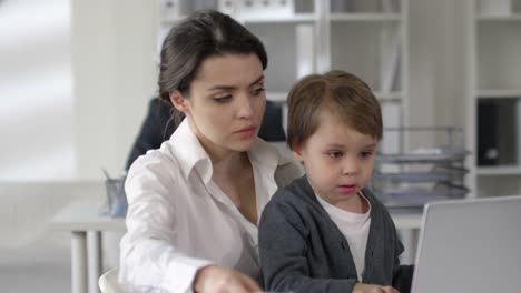 Beschäftigte-Mutter-verbringt-Arbeitstag-mit-kleinem-Sohn-im-Büro