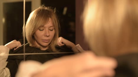 Close-up-of-a-girl-magician-in-front-of-a-mirror-puts-on-the-hood-of-his-suit-time-after-time.-Live-camera.