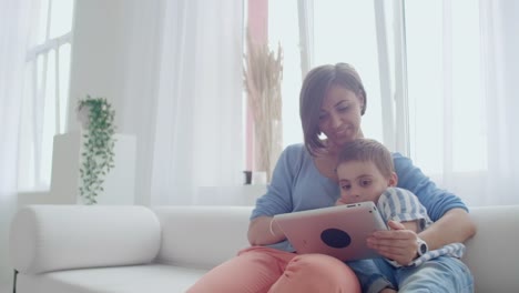 Madre-e-hijo-jugando-con-la-tableta-digital-en-casa.-Joven-madre-con-sus-5-años-sonriendo-con-tableta-digital-en-casa.