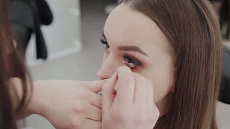 Professionelle-Make-up-Künstler-Frau-malt-Wimpern-an-Kunden-des-Schönheitssalons