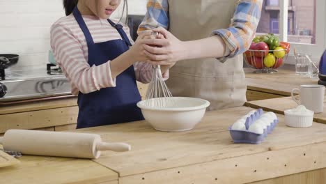 mother-helping-kid-stir-mix-in-bowl-teaching