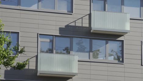 Close-up-shot-of-residential-building.-Apartment-building-exterior-with-reflection-in-windows.-The-building-features-exterior-with-small-balconies