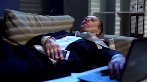 Tired-businessman-is-sleeping-on-the-sofa-at-the-office