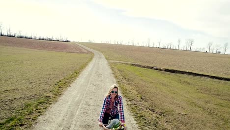 Junge,-hübsche,-Rubio-frau-fährt-auf-fahrrad-vintage-auf-einem-feldweg