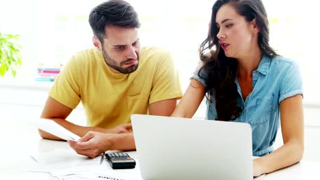 Worried-couple-calculating-their-bills-with-laptop-in-the-kitchen