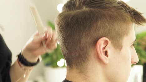 Hairdresser-cutting-male-hair-with-electric-shaver-in-beauty-school.-Woman-haircutter-making-male-haircut-with-hair-clipper-in-barbershop-close-up