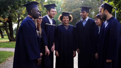 happy-students-in-mortar-boards-with-hands-on-top