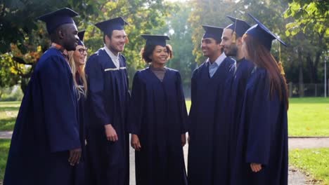 happy-students-in-mortar-boards-making-high-five