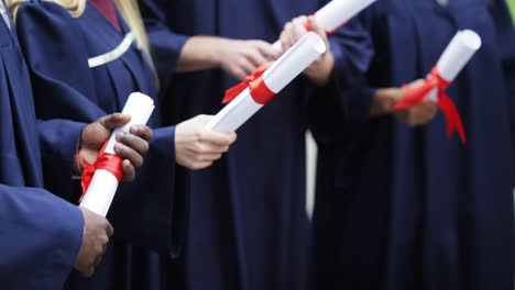 glückliche-Schüler-in-Mörtel-Boards-mit-Diplomen